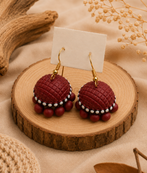 Add a fluid grace to your ethnic ensemble with the Ruby Weave Terracotta Hanging Jhumkas. Featuring flowing wave-inspired artistry and rich ruby-toned craftsmanship, these handcrafted clay earrings move with pure elegance.