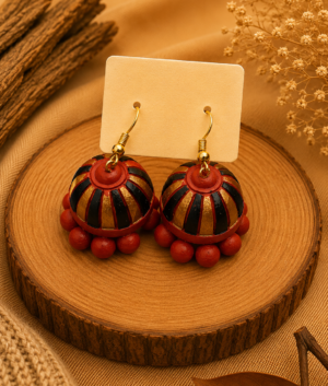 Sunset Spin handmade terracotta hanging jhumka earrings featuring a hand-painted spiral design in vibrant orange, red, and gold tones.